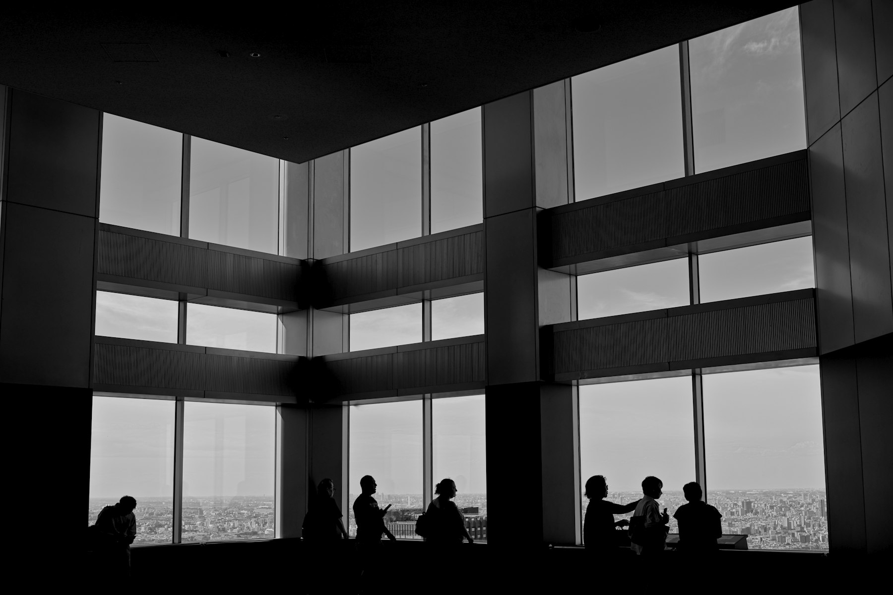 Executives in silhouette in front of floor-to-ceiling windows overlooking a city